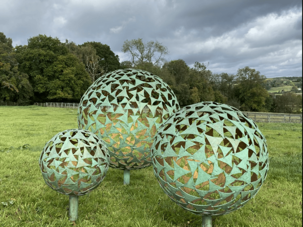 IMG 4376.HEIC Trio of Sphere Sculpture Our NEW Trio of Sphere Sculpture, three different size spheres arranged in a triangular layout, these spheres together can create that huge wow factor to your outdoor or indoor space. Our spheres are also available individually, please see our shop. We are able to offer all our sphere styles & finishes in this trio of sphere sculpture.   This selection of spheres displayed here are our Verdigris & Gold 1.5m, 1m & 65cm - Prices may vary, dependant on the sizes you choose, also styles and finishes can affect costs.   *Additional Charges for Installation, Delivery & Illumination Kits Available On Request.   Our Verdigris & Gold Spheres Handmade in Buckinghamshire Designed and Handcrafted by Elliott of London from mild steel with a luxurious progressive Verdigris Aged Bronze Exterior and glowing Gold gilt Interior. This piece is hot zinc galvanised initially to secure and protect the piece from nature and rust for over 30 years. "Each sail piece individually textured and finished with a luxurious patina by hand!" Designer Charles. Inspired by nature, with weather aged Patina on the outside with new bright gold on the inside.It can be used as a garden vocal point or also as an interior piece, it can be scaled down accordingly and illuminated internally. Available floating above ground level or raised on a choice of stone plinths. Illumination Kits available. Alternative sizes and alternative finished plinths are available at additional costing - please call for more information.   All Enquiries Welcome Worldwide Shipping & Installation Available   We Welcome Studio Visits - By Appointment Only www.elliottoflondon.co.uk info@elliottoflondon.co.uk 01494 758 896